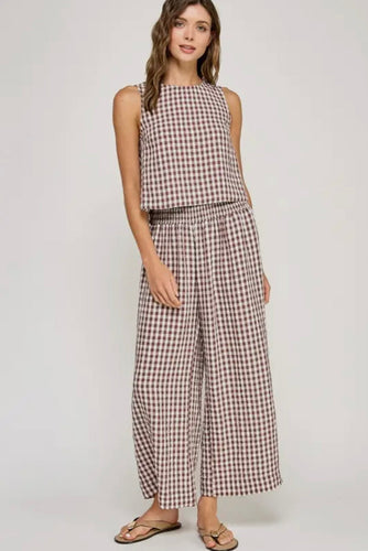 Woman wearing a checkered sleeveless top and wide-leg pants on a white background