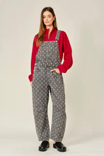 Load image into Gallery viewer, A woman modeling a pair of gray wide-leg overalls with a white polka dot pattern, worn over a red long-sleeve mock neck top and paired with black shoes, against a light beige studio background.