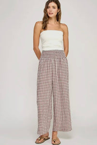 Woman wearing a white strapless top and plaid pants on a plain background
