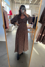 Load image into Gallery viewer, Person wearing a brown floral dress in a store setting