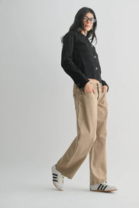 Person wearing a black cardigan and beige pants on a white background