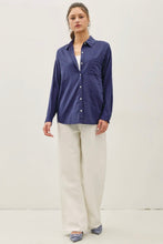 Load image into Gallery viewer, A woman modeling a long-sleeve button-up shirt in navy blue, paired with wide-leg cream trousers and blue pointed flats, against a plain off-white studio background.