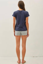 Load image into Gallery viewer, A woman viewed from behind wearing a short-sleeve navy blue t-shirt and light gray heathered shorts, standing against a plain white studio background.