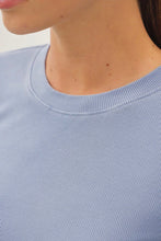 Load image into Gallery viewer, Close-up of a person wearing a light periwinkle blue ribbed crewneck top, showing the collar and upper chest area.