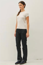 Load image into Gallery viewer, A woman modeling a fitted off-white short-sleeve crewneck t-shirt and dark wash straight-leg jeans with black sneakers, standing against a plain light gray studio background.