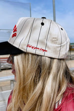 Load image into Gallery viewer, A woman wearing a baseball cap with a cream pinstripe design, black brim, and red embroidered text reading 'Out of Game League' on the side. The photo is taken from behind, showing her blonde hair and a red top against an outdoor background.