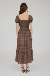 Woman wearing a brown plaid dress on a white background