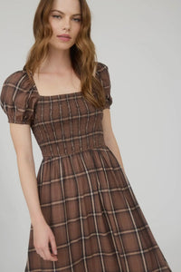 Woman wearing a brown plaid dress on a white background