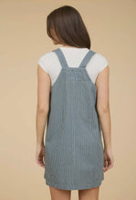 Load image into Gallery viewer, Woman wearing a blue pinafore dress over a white shirt on a beige background
