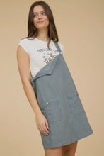 Load image into Gallery viewer, Woman wearing a white t-shirt with text and graphics, paired with a gray checkered apron on a beige background