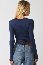 Load image into Gallery viewer, A woman shown from the back wearing a navy blue long-sleeve top and light blue jeans against a plain light gray background.
