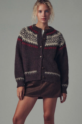 Woman wearing a dark brown knitted cardigan with a patterned design on a gray background