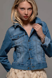 Woman wearing a blue denim jacket against a gray background