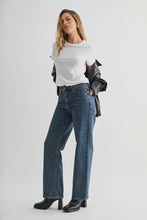 Load image into Gallery viewer, Woman wearing a white t-shirt, blue jeans, and a black leather jacket on a light gray background