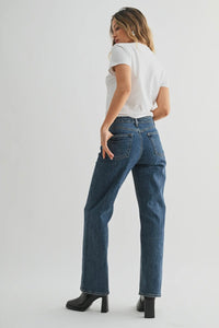 Woman wearing blue jeans and a white t-shirt on a plain background