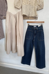 Stack of folded jeans and shirts on a white surface