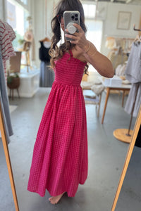 Woman in a red checkered dress taking a mirror selfie in a store.