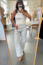 Load image into Gallery viewer, Person taking a mirror selfie wearing a white tank top and light blue jeans in a room.
