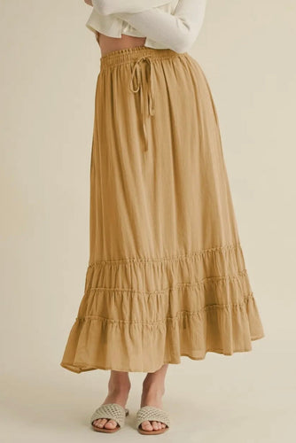 Beige tiered skirt worn by a person on a beige background