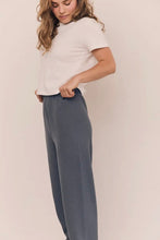 Load image into Gallery viewer, Woman wearing a white top and gray pants against a plain background