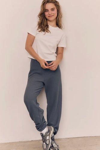 Person wearing a white t-shirt and blue pants against a plain background