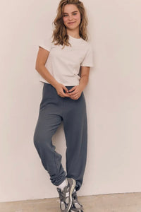 Person wearing a white t-shirt and blue pants against a plain background