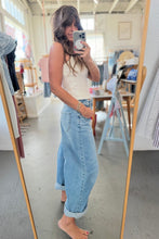 Load image into Gallery viewer, A woman takes a mirror selfie in a boutique, wearing a cream ribbed tank top and light-wash wide-leg denim jeans with rolled cuffs.