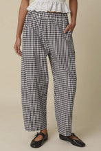 Load image into Gallery viewer, Person wearing black and white checkered pants on a beige background