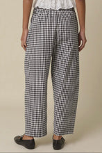 Load image into Gallery viewer, Person wearing black and white checkered pants on a beige background