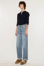 Load image into Gallery viewer, A model stands against a plain white studio background wearing a dark navy long-sleeve polo shirt, light-wash wide-leg blue jeans, and brown suede shoes.