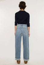 Load image into Gallery viewer, A model viewed from the back wearing light-wash wide-leg jeans, a dark navy long-sleeve top, and brown shoes against a plain white studio background.