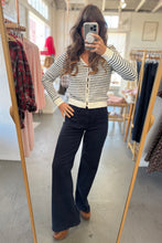 Load image into Gallery viewer, Person wearing a striped sweater and black pants in a clothing store.