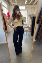 Load image into Gallery viewer, Person taking a mirror selfie wearing a cream top and dark blue jeans in a clothing store.