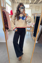 Load image into Gallery viewer, Person wearing a patterned sweater and black pants in a clothing store.