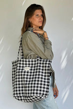 Load image into Gallery viewer, Woman holding a black and white checkered bag against a white background
