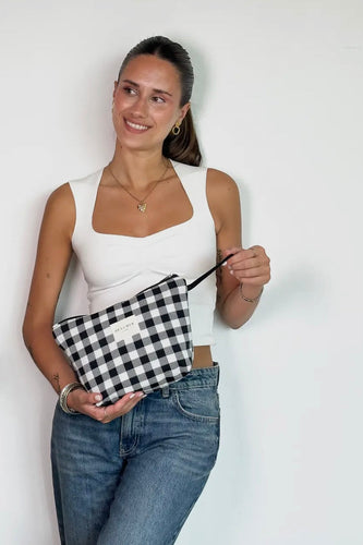 Woman holding a black and white checkered pouch against a white background