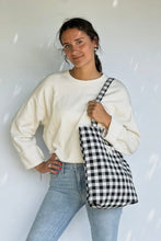 Load image into Gallery viewer, Woman holding a black and white checkered bag against a white background