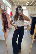 Load image into Gallery viewer, Person taking a mirror selfie wearing a striped shirt and dark pants in a clothing store.