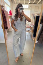 Load image into Gallery viewer, Person wearing light blue overalls taking a mirror selfie in a clothing store.