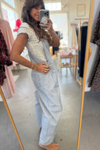 Load image into Gallery viewer, Woman taking a mirror selfie wearing a light blue denim jumpsuit in a clothing store.