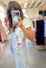 Load image into Gallery viewer, Woman taking a mirror selfie in a clothing store wearing a white lace top and light blue denim jacket.