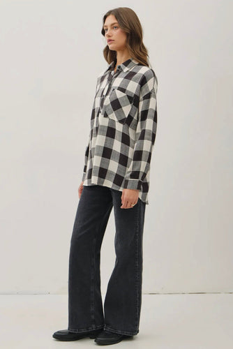 Woman wearing a black and white checkered shirt and dark jeans on a white background