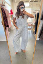 Load image into Gallery viewer, Person wearing light blue overalls taking a mirror selfie in a clothing store.