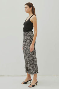 Woman wearing a black tank top and floral skirt against a white background