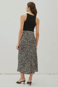 Woman wearing a black floral skirt and black top on a white background