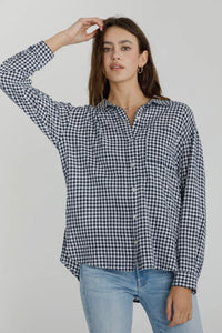 Woman wearing a black and white checkered shirt and blue jeans against a plain background