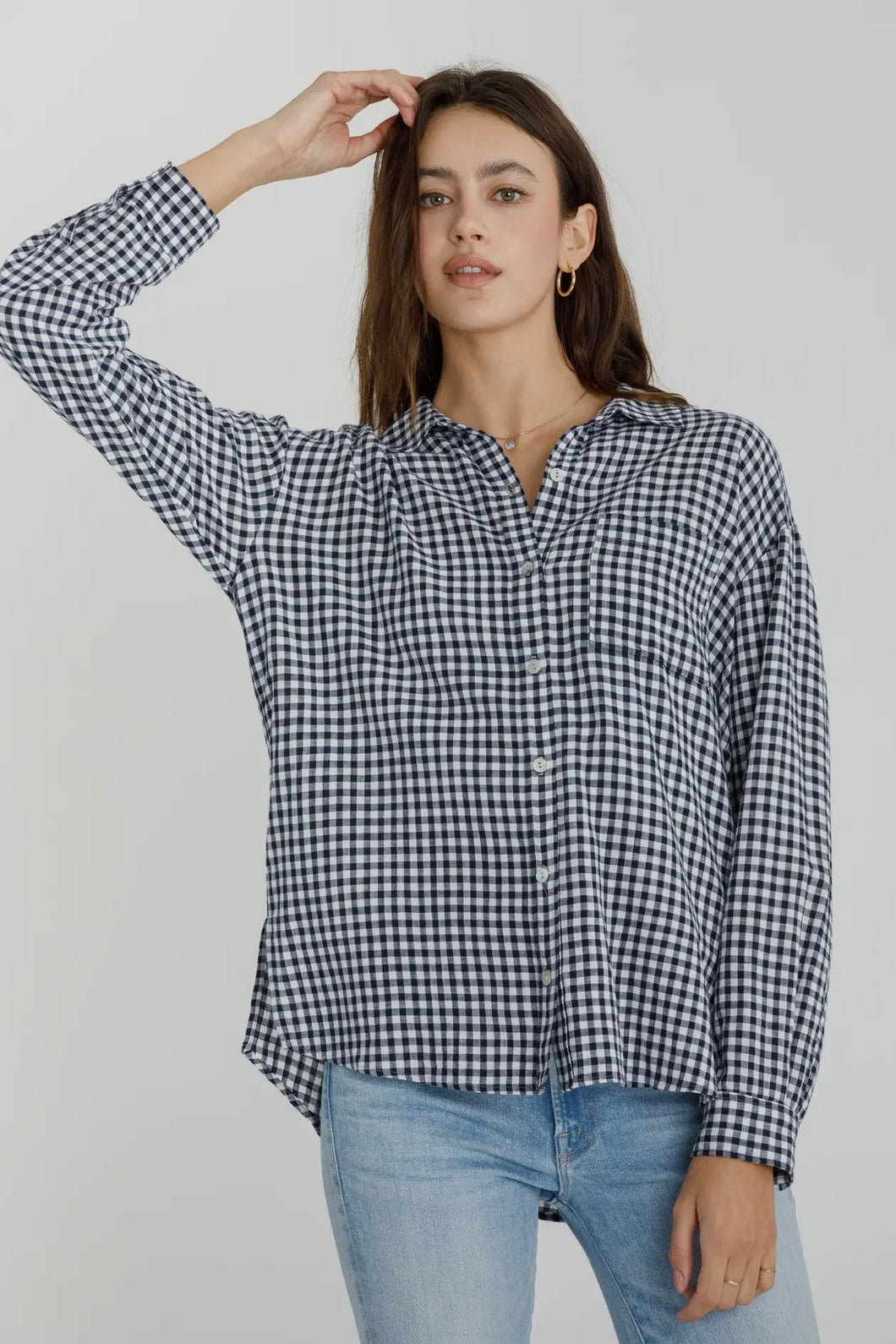 Woman wearing a black and white checkered shirt and blue jeans against a plain background