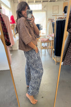Load image into Gallery viewer, Person taking a mirror selfie wearing a brown sweater and blue patterned pants in a clothing store.