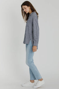Woman wearing a checkered shirt, light blue jeans, and white sneakers on a white background