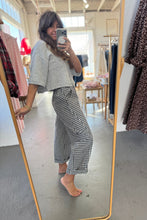 Load image into Gallery viewer, Person taking a mirror selfie wearing a gray top and checkered pants in a clothing store.
